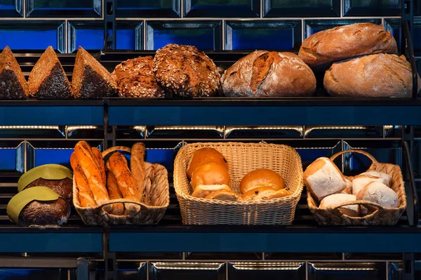 Freshly baked bread on a shelves in bakery, baguette and rolls. Different types of delicious loaves of bread in a german baker shop.