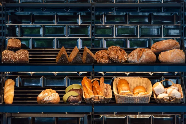 Freshly baked bread on a shelves in bakery, baguette and rolls. Different types of delicious loaves of bread in a german baker shop.