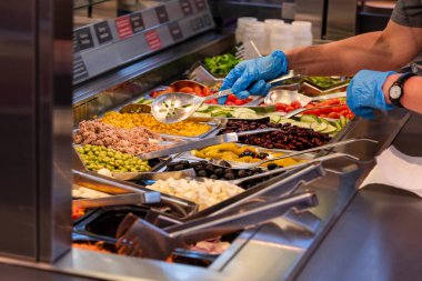 Choosing food from buffet. Fresh salad bar with a variety of fresh vegetables, vegetable table for customers to choose from in a supermarket or restaurant. Buffet in the hotel.