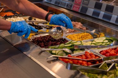 Choosing food from buffet. Fresh salad bar with a variety of fresh vegetables, vegetable table for customers to choose from in a supermarket or restaurant. Buffet in the hotel.
