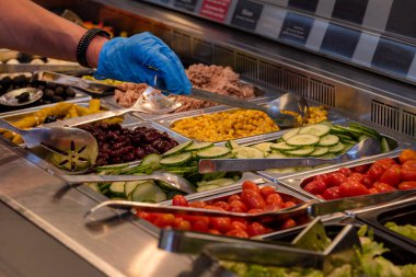 Choosing food from buffet. Fresh salad bar with a variety of fresh vegetables, vegetable table for customers to choose from in a supermarket or restaurant. Buffet in the hotel.