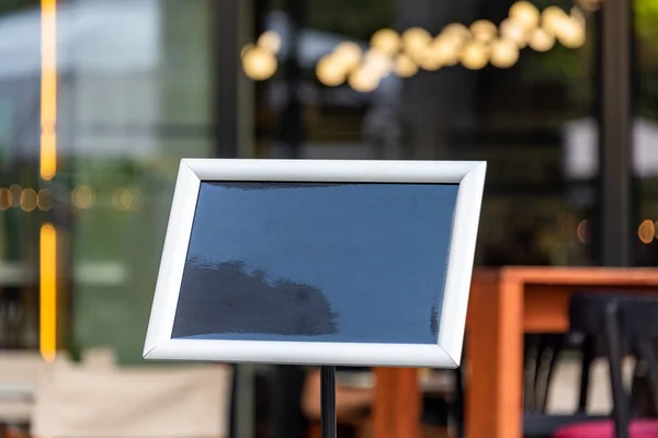 Blank restaurant shop sign or menu board near the entrance to restaurant. Cafe menu on the street. Blackboard sign mockup in front of a restaurant. Signboard, empty blackboard.