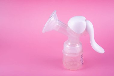 Pembe arka planda elle göğüs pompası. Emziren anne için süt temini sağlayan bir cihaz. Annelik ve bebek bakımı kavramı