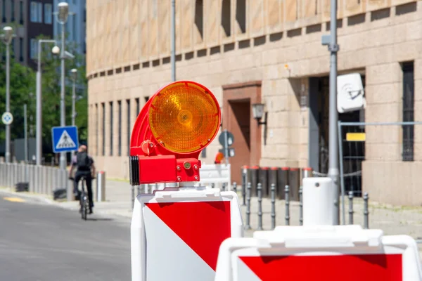 Red and white street barriers with flashlight to secure a construction site, roadworks, road under construction. Temporary fencing, repair on the city street, closed for renovation. No way, stop and detour sign