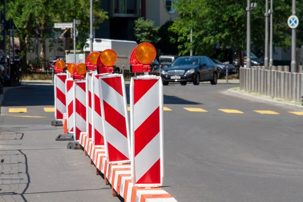 Red and white street barriers with flashlight to secure a construction site, roadworks, road under construction. Temporary fencing, repair on the city street, closed for renovation. No way, stop and detour sign