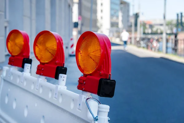 Red and white street barriers with flashlight to secure a construction site, roadworks, road under construction. Temporary fencing, repair on the city street, closed for renovation. No way, stop and detour sign