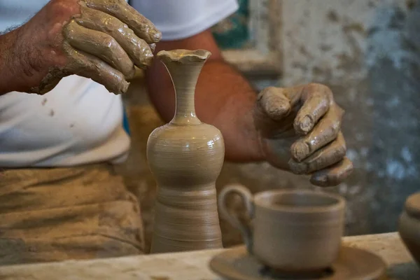 Pottery workshop hands work with clay. A man makes a vase of liquid clay with his hands. Ceramic vase and cup manufacturing process. Do it yourself master class. Place for your text.