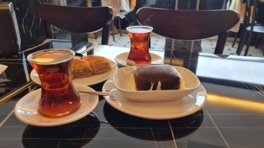 Geleneksel bardakta Türk çayı ve masada tatlılar. Türk çayı ve tatlı.