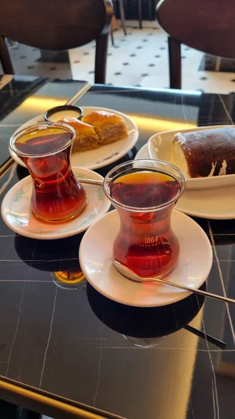 Турецкий чай в традиционных стаканах с десертами на столе. Турецкий чай с десертом — стоковое фото