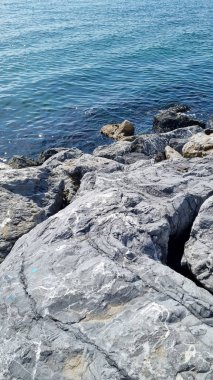 Beyaz-gri köpüklü Barents Denizi. Tepeler ve ufuktaki koyu mavi bulutlar. Kuzeye. Soğuk su. Kuzey Buz Denizi.