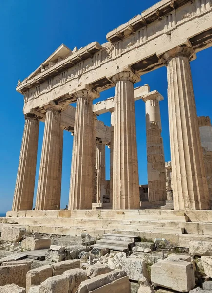 Acropolis, ancient Greek fortress in Athens, Greece. Panoramic image of Parthenon temple on a bright day with blue sky and faraway clouds. Classical Greek heritage