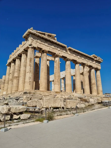 Acropolis, ancient Greek fortress in Athens, Greece. Panoramic image of Parthenon temple on a bright day with blue sky and faraway clouds. Classical Greek heritage