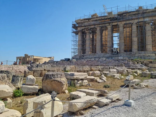 Acropolis, ancient Greek fortress in Athens, Greece. Panoramic image of Parthenon temple on a bright day with blue sky and faraway clouds. Classical Greek heritage