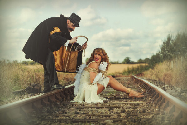 Pretty woman tied up on railway line by classic villain