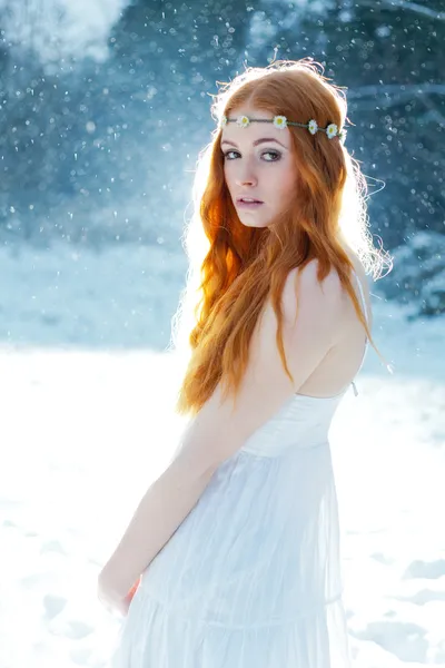 Sneeuw meisje. fantasie beeld van prachtige rood hoofd vrouw permanent in sneeuw, camera kijken — Stockfoto