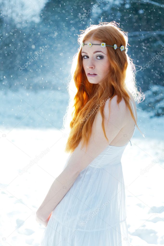 Snow Maiden. Fantasy image of beautiful red head woman standing in snow, looking at camera