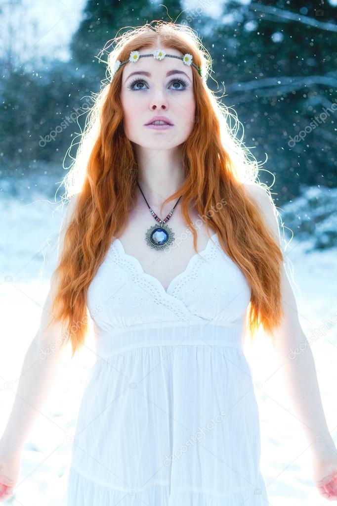 Snow Maiden. Whimsical image of beautiful red head woman standing in snow looking angelic