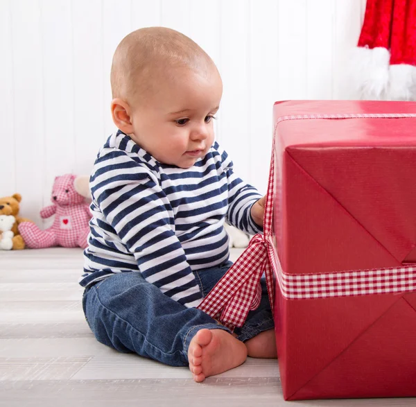 Primeiro Natal: bebê desembrulhando um presente — Fotografia de Stock