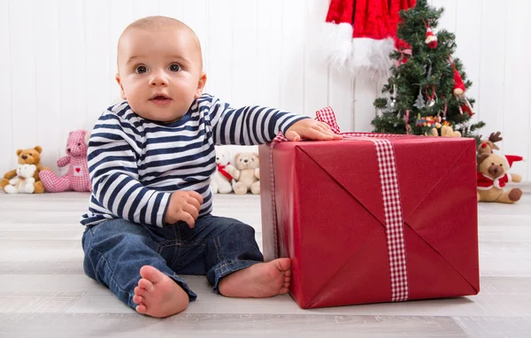 First Christmas: baby unwrapping a present — Stock Photo, Image
