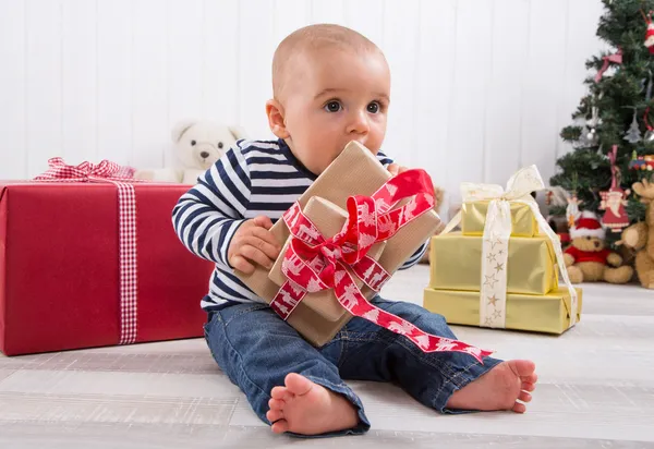 First Christmas: baby unwrapping a present — Stock Photo, Image