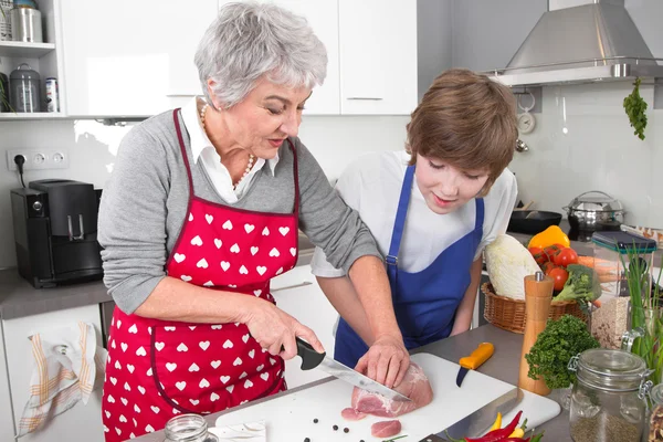 Grand-mère enseigner aux jeunes garçons à cuisiner la viande - la vie de famille à hom — Photo