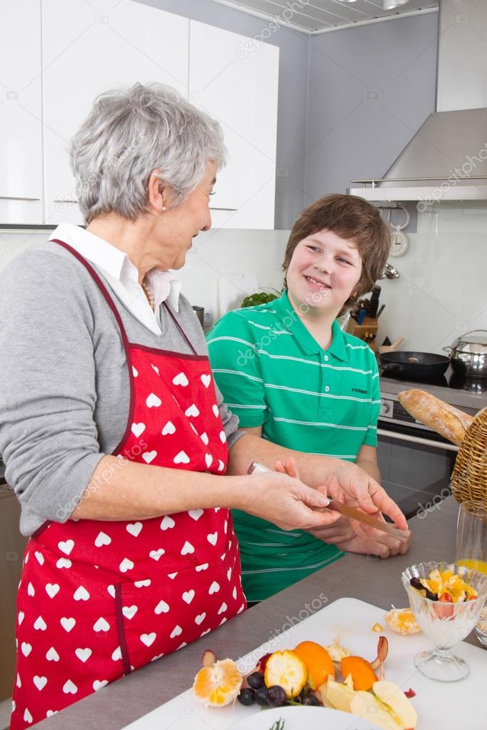 Grandmother teaching young boy to cook meat - family life at hom