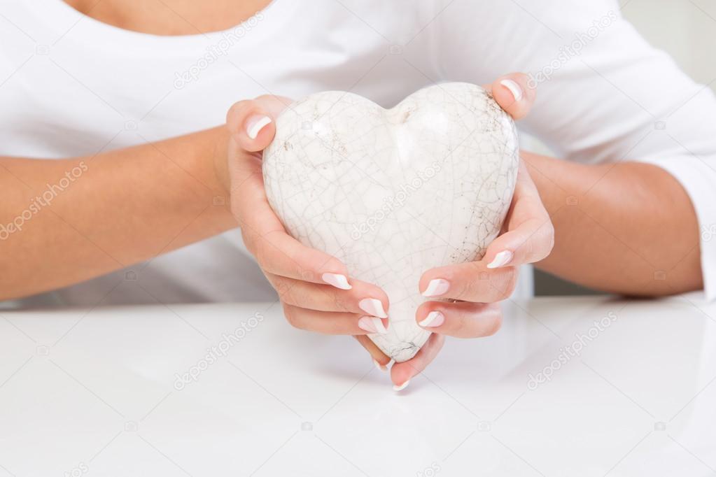 Female hands with white decorated heart