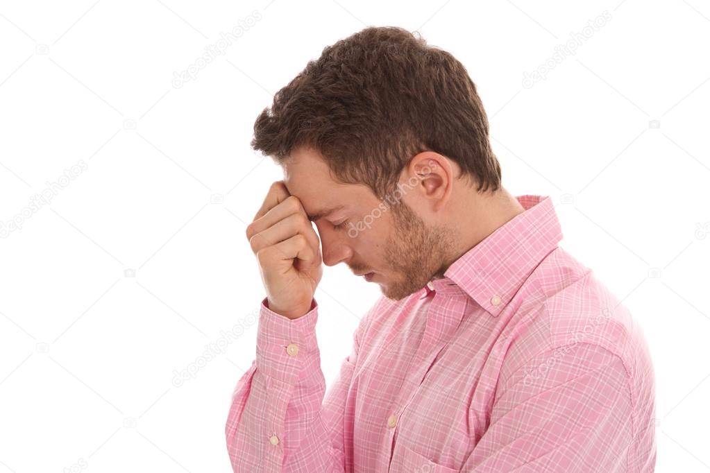 Profile: stressed young business man in pink with head in hands
