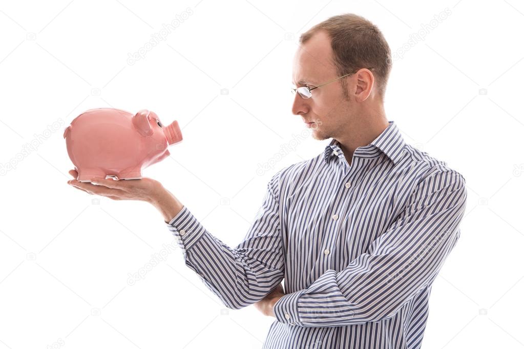 Young man looking at pink piggy bank isolated