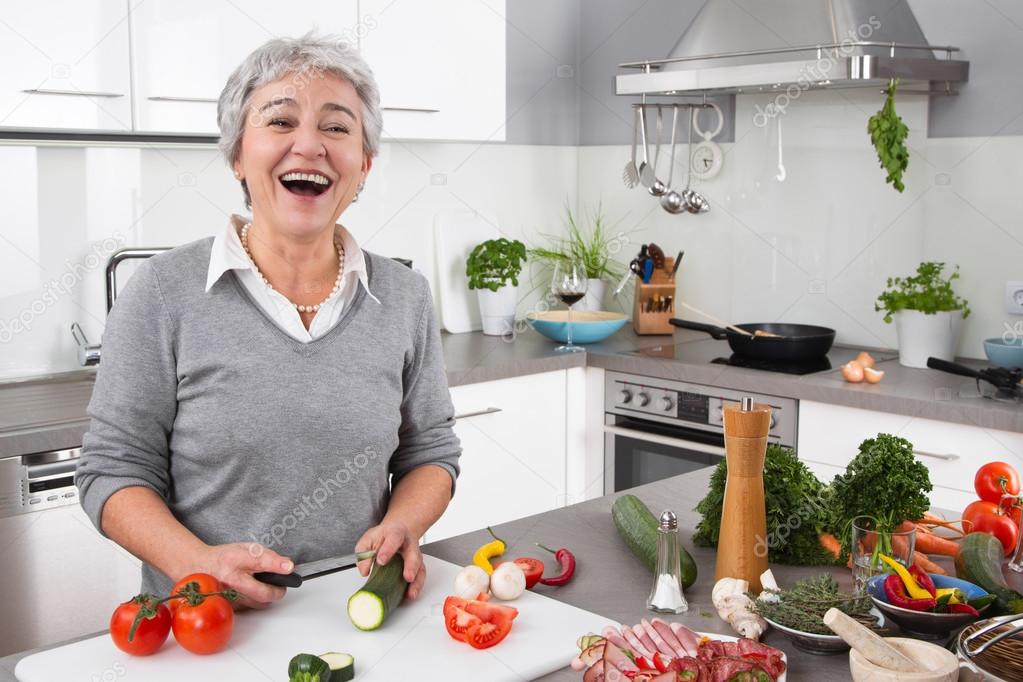 Senior or older woman with grey hair cooking in kitchen