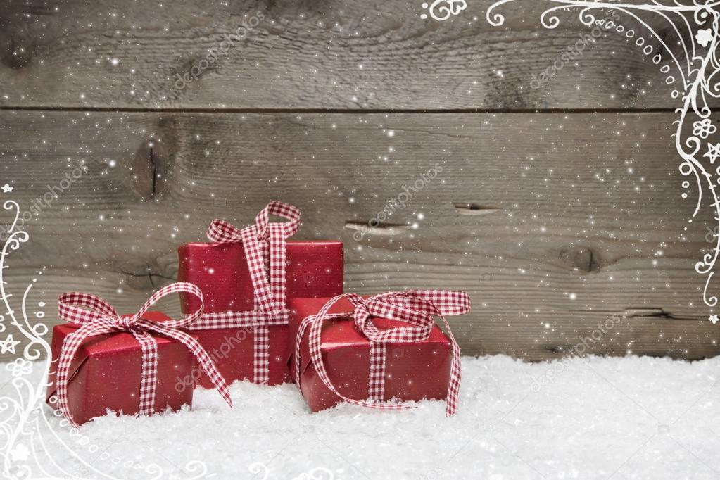 Group of red Christmas presents, with snow on grey wooden background - idea for a greeting card or coupon with a red checkered ribbon