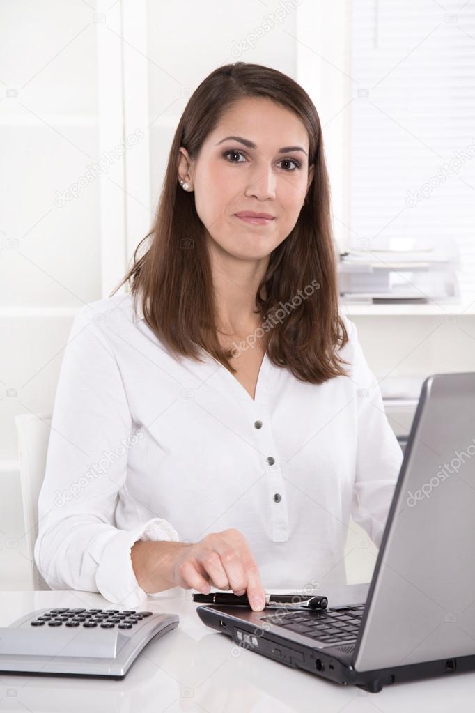 Young smiling businesswoman at desk in a bank