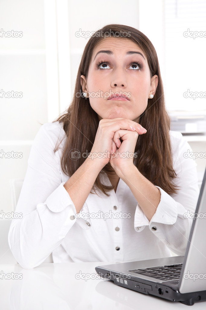 Bored businesswoman at desk looking up from laptop