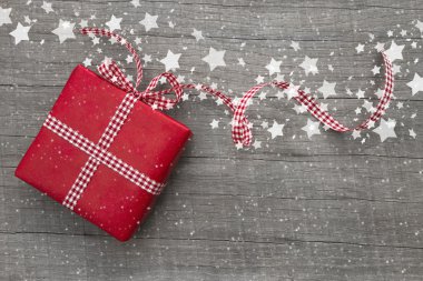 bir tebrik kartı için ahşap arka plan üzerinde kırmızı kağıt sarılı bir Noel hediyesi