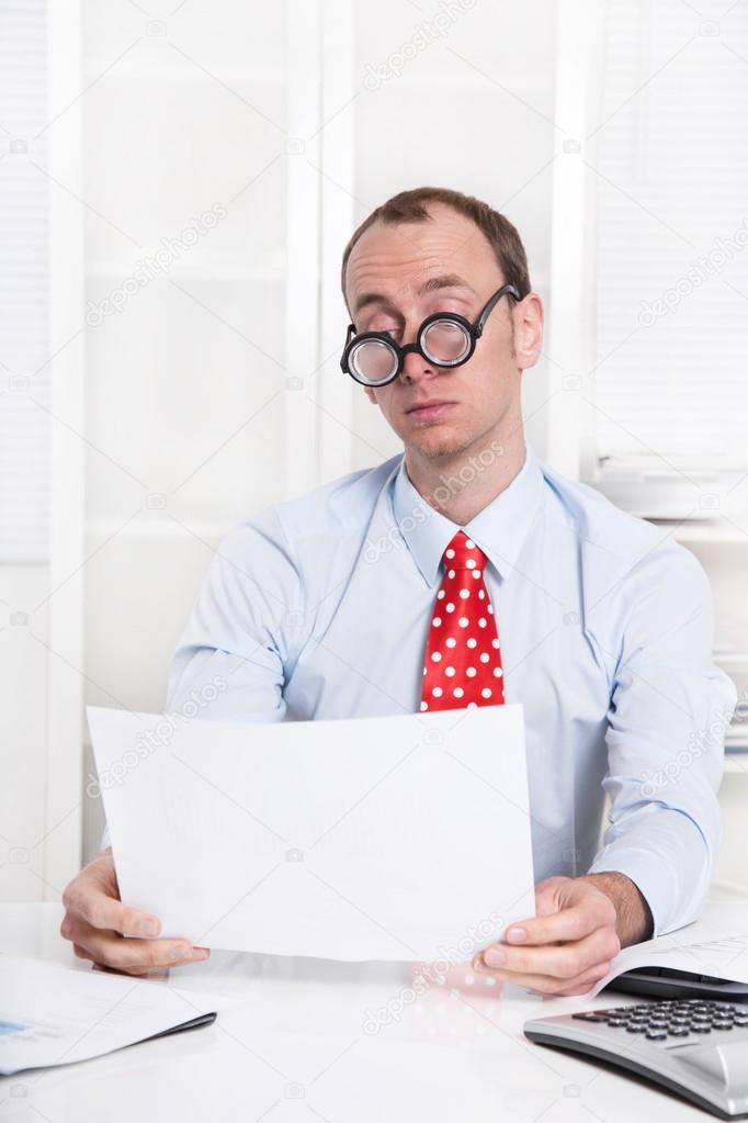 Overworked and tired businessman with glasses reading at desk