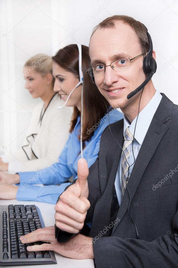 Agent smiling while working on his computer in a call-center.