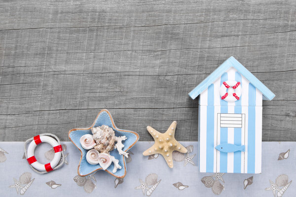 Beach hut and seashells on a grey wooden background for travel concepts