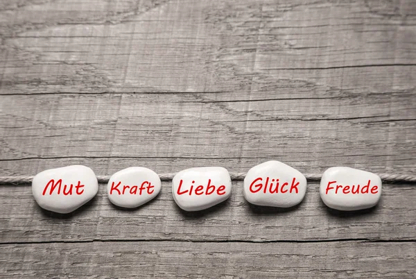 Steine mit deutschen Worten für Liebe auf Holzgrund. — Stockfoto