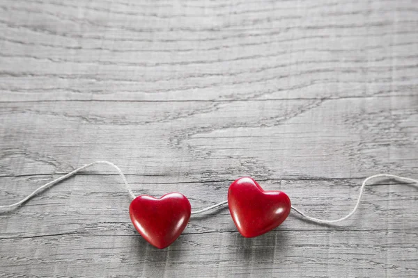 Twee rode harten op een houten shabby achtergrond voor Valentijnskaart. — Stockfoto