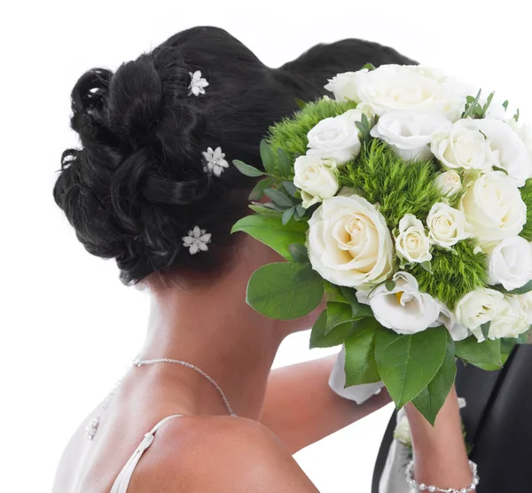 Kyssa bruden och brudgummen gömd bakom brud bukett isolerad på — Stockfoto