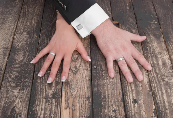 Wedding theme, man and woman hands on a wooden floor — Stock Photo, Image