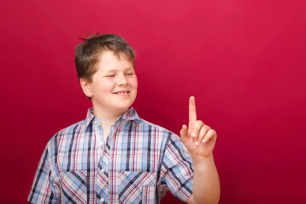 Boy points up on red background — Stock Photo, Image