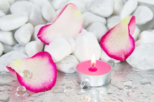 Лепестки роз и зажженная свеча для украшения спа — стоковое фото