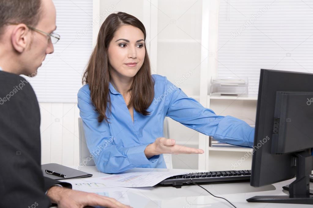 Two business people talking together at desk - adviser and custo