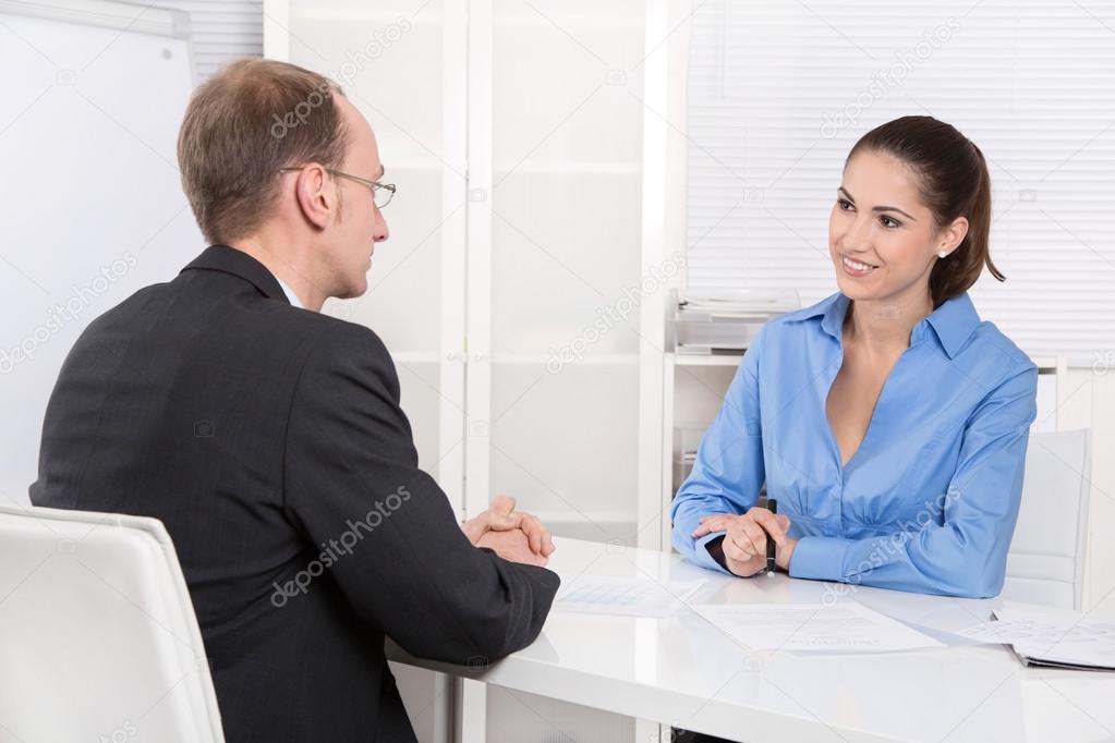 Two business people talking together at desk - adviser and custo