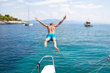 genç adam bir yelkenli tekne atlama.