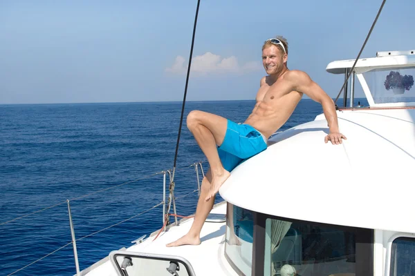 Blond knappe jonge man op zeilboot. — Stockfoto