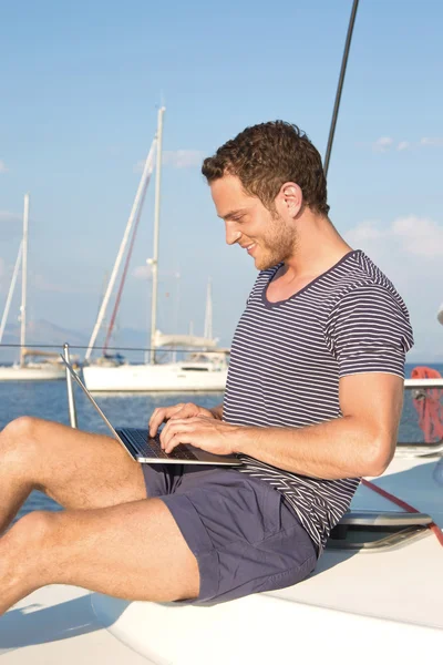 Zakenman werkt met laptop tijdens vakantie op een zeilboot — Stockfoto