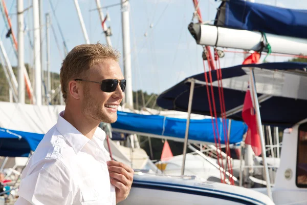 Attractive young man at seaport in front of sailing boat - harbo — Stock Photo, Image