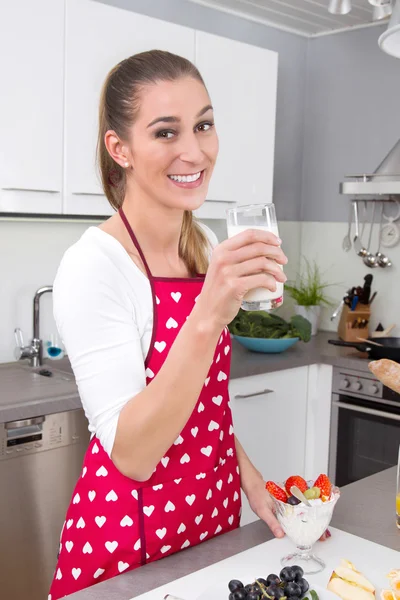 Mladá žena pije sklenici mléka v kuchyni. — Stock fotografie